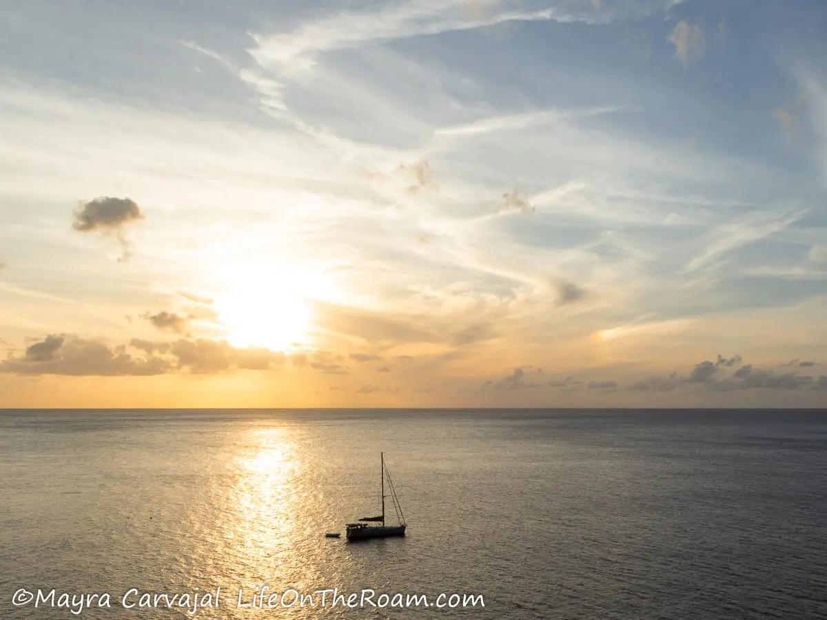 A sunset over the sea with a boat sailing
