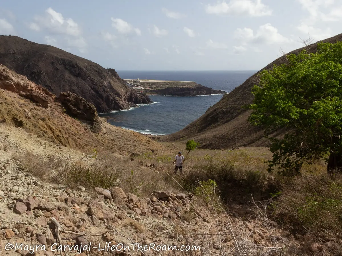 A trail on a hill with loose rocks and a bay in the distance